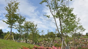 Un camí de pedra que travessa un jardí amb flors roses i arbres.