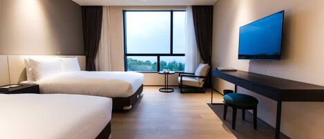 A modern hotel room with two beds, a desk, a chair, a TV, and a large window offering a view of the outdoors.