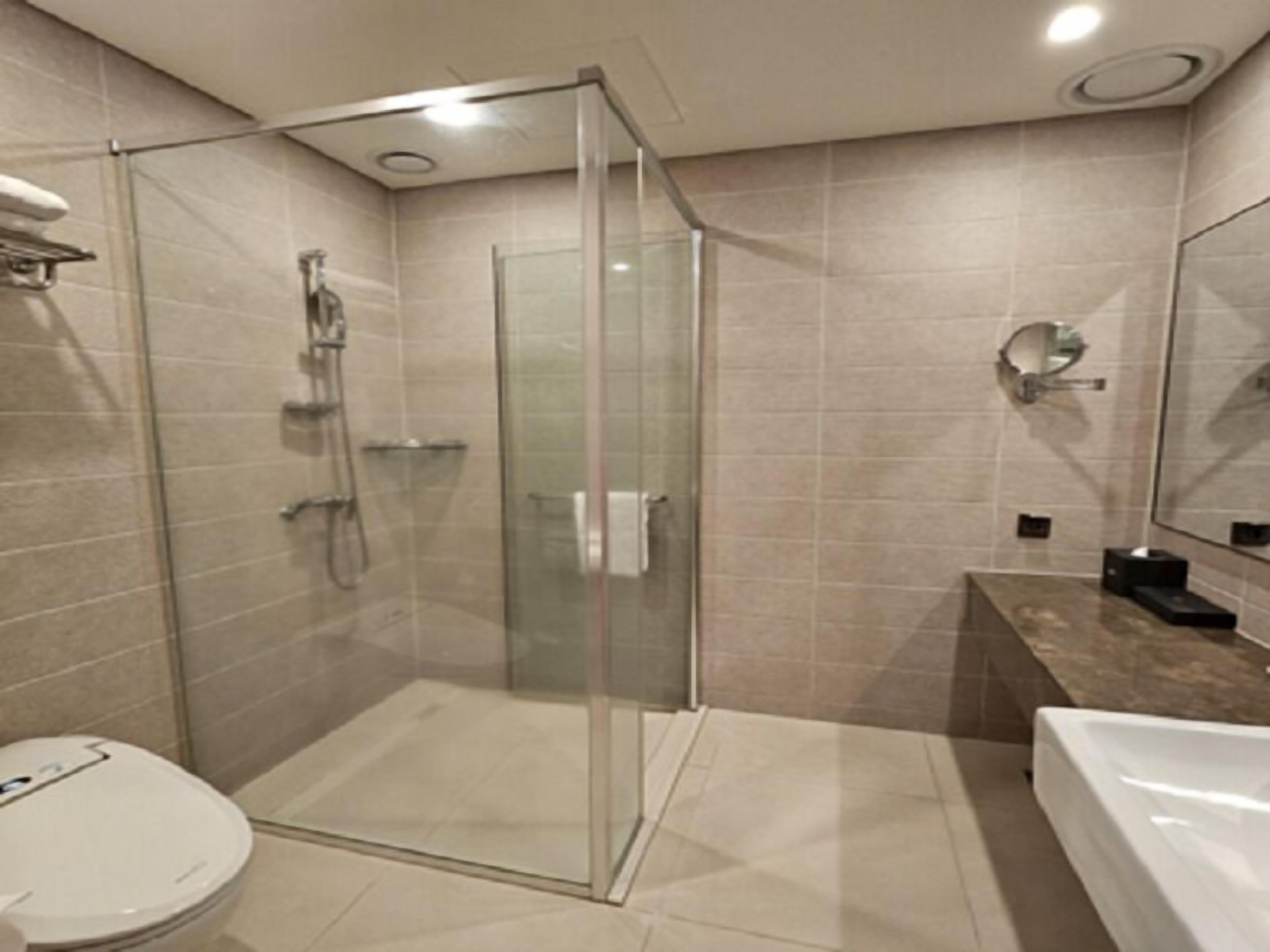 A modern bathroom with a glass-enclosed shower, a white toilet, and a large bathtub.