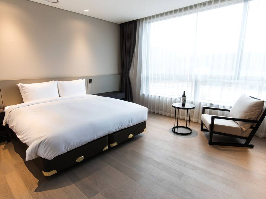 A modern hotel room with a large bed, a small round table, and a chair.