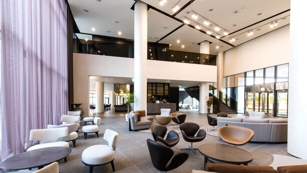A spacious lobby with multiple seating areas, a staircase, and large windows. - Hotel Nanta Jeju (Jeju City)