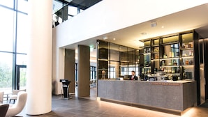A modern restaurant with a reception desk, a bar area, and a seating area with a large window. - Hotel Nanta Jeju (Jeju City)