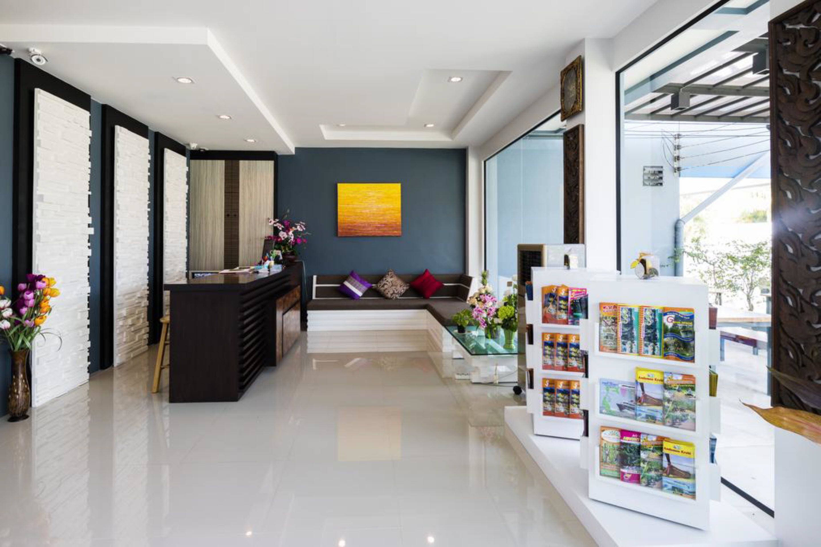 A modern reception area with a black reception desk, a seating area with cushions, and a display of travel brochures.