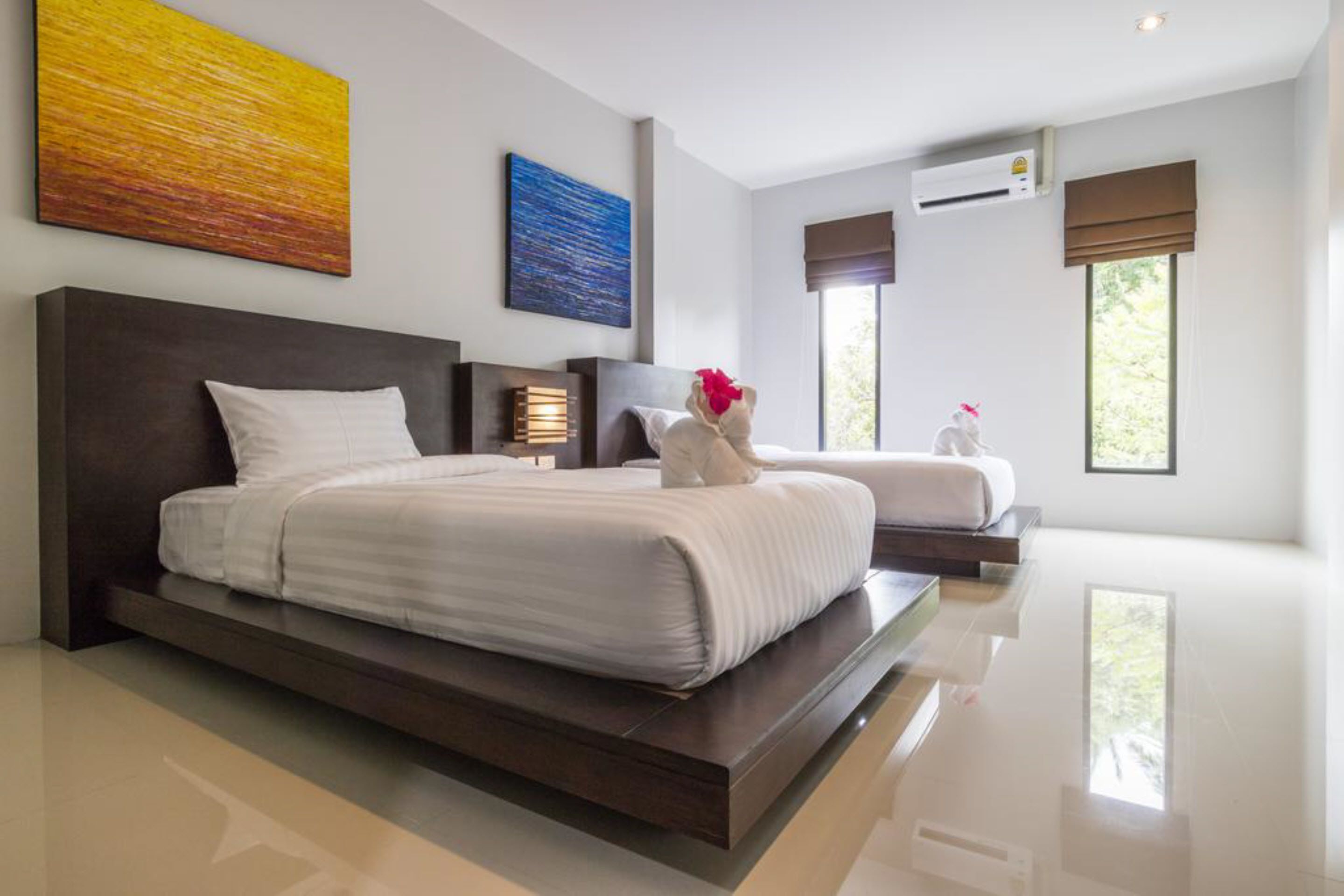 Una habitación de hotel moderna con una cama grande, otra más pequeña y una zona de estar.