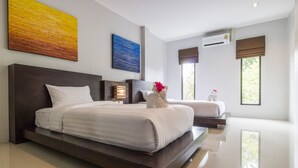 Une chambre d’hôtel moderne avec un grand lit, un lit plus petit et un coin salon.