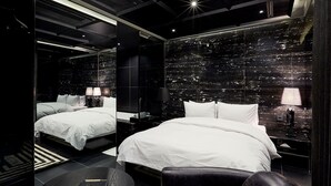 A modern hotel room with a large bed, two bedside tables, a round table, and a cityscape view through the glass wall. - Hotel The Artist Yeoksam (Seoul)