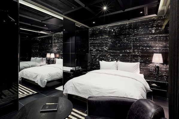 Habitación de hotel moderna con una cama grande, dos mesitas de noche, una mesa redonda y vistas a la ciudad a través del muro de cristal.
