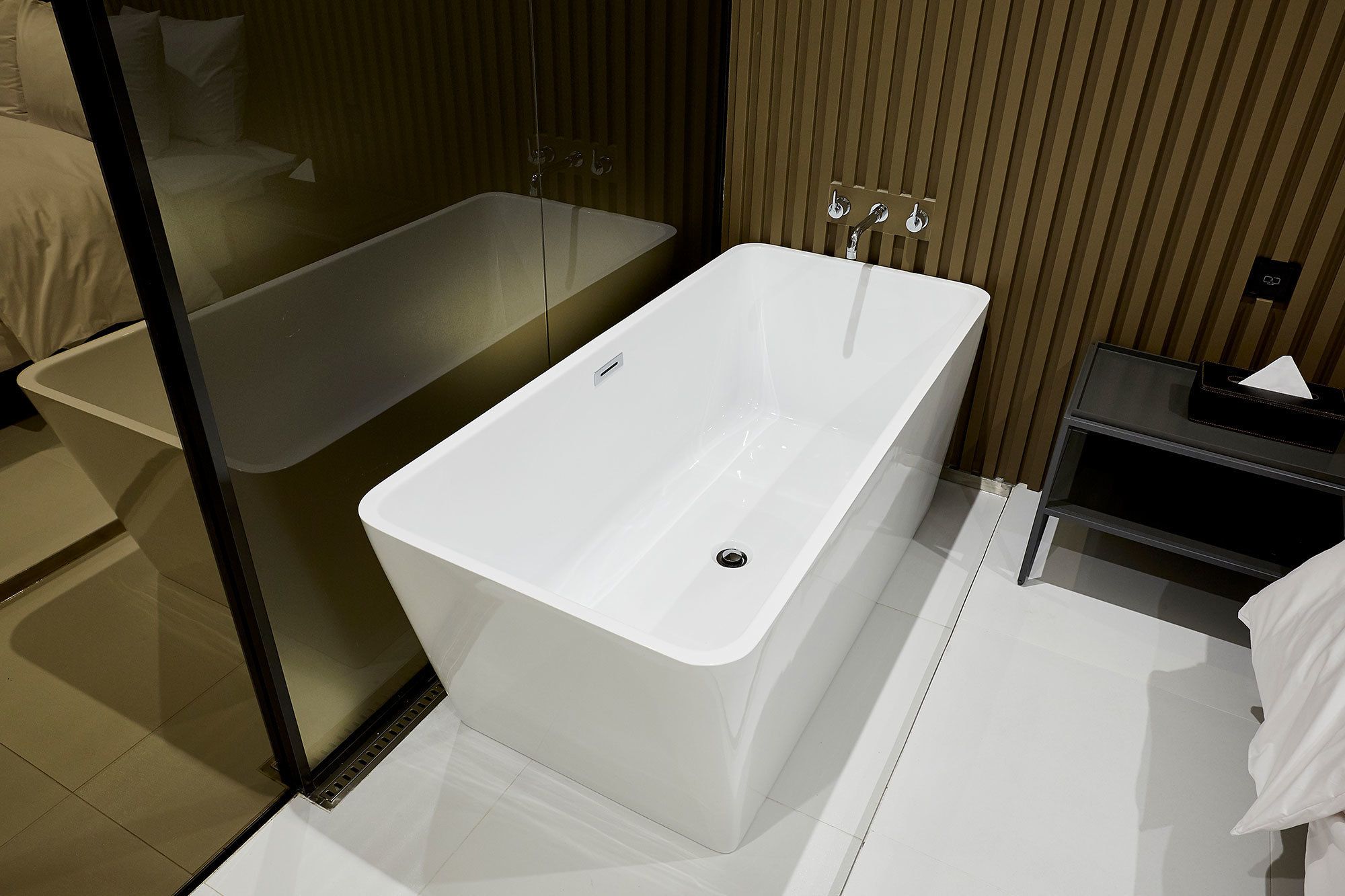 Un baño moderno con una bañera independiente, cabina de ducha con paredes de cristal y un mueble de tocador con toallero.