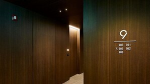 A hallway with wooden paneling and a lit exit sign. - Hotel The Artist Yeoksam (Seoul)