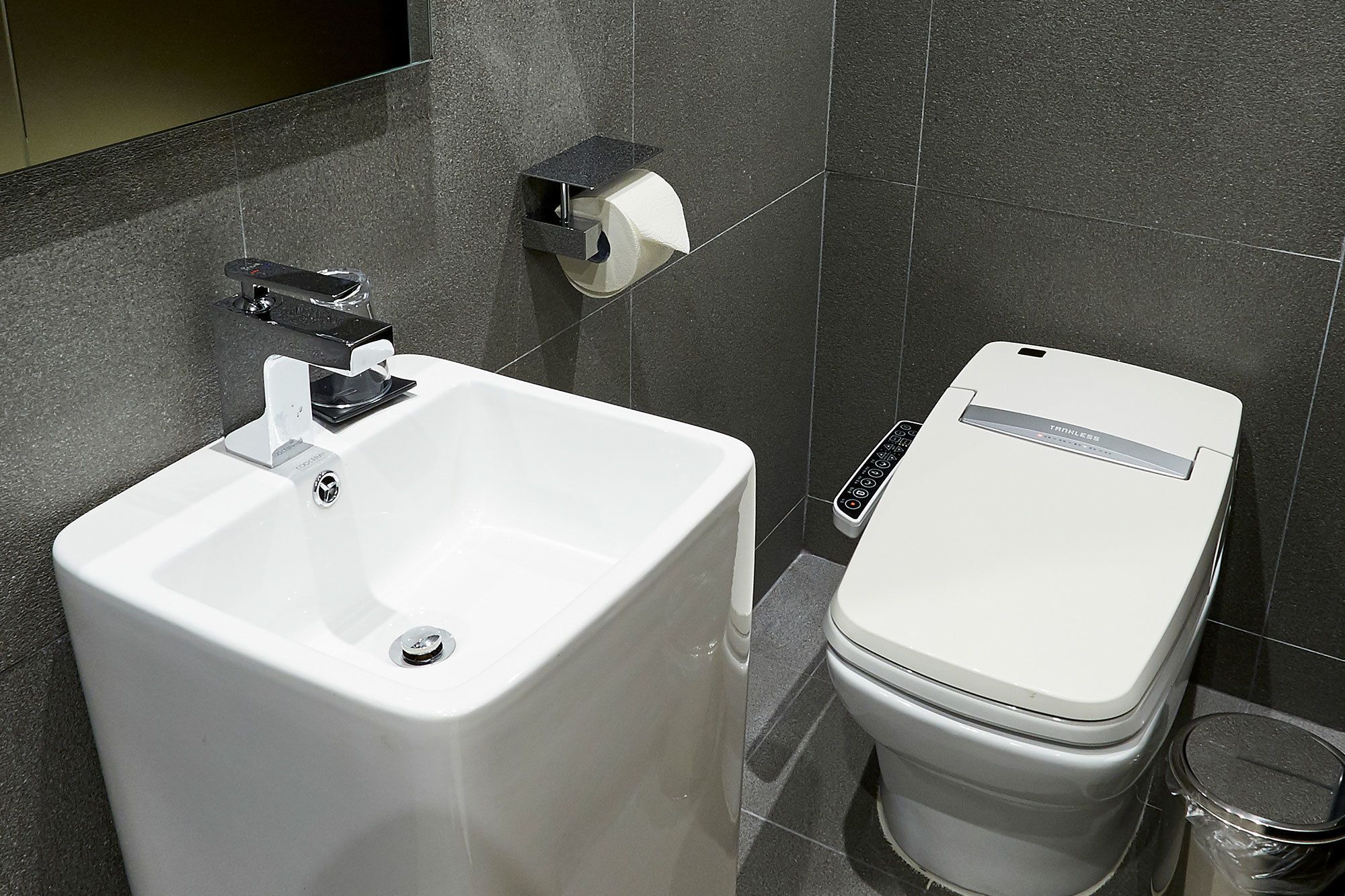 Un bagno moderno con un lavandino, un water e un cestino bianco.