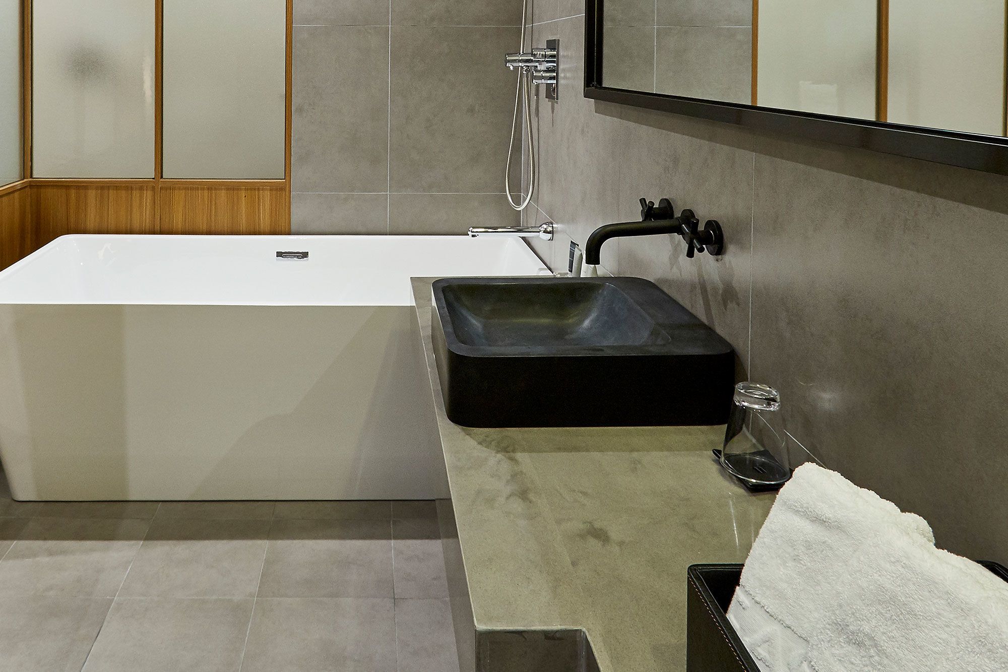 Ein modernes Badezimmer mit einer freistehenden Badewanne, einem schwarzen Waschbecken und einem Spiegel darüber.