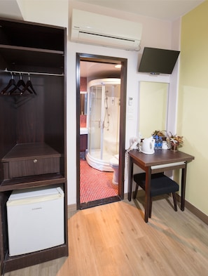 A hotel room with a walk-in closet, a small table with toiletries, and a shower area.
