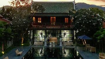 Uma casa de dois andares com uma piscina em frente.
