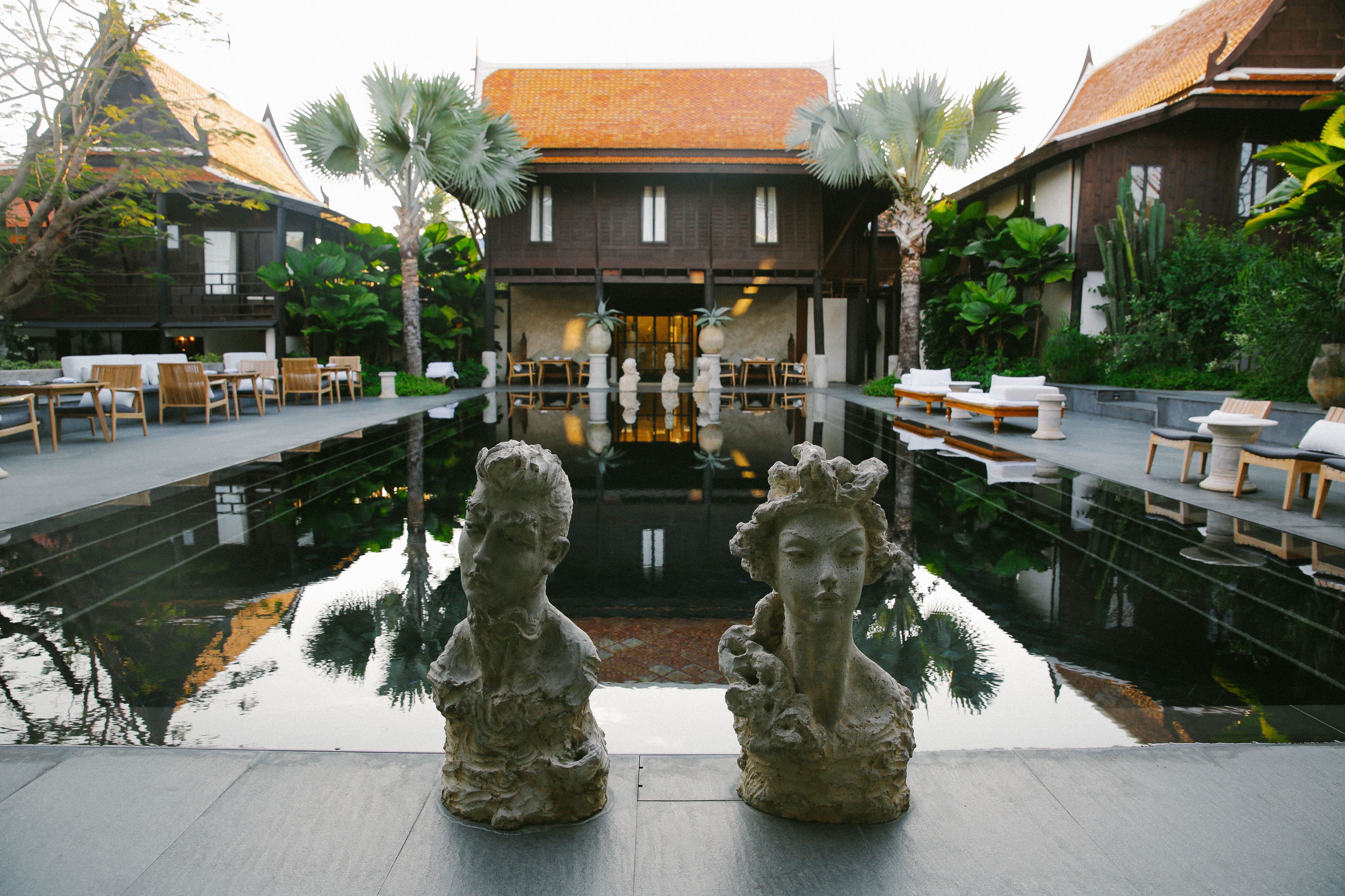 A courtyard with a reflective pool, stone sculptures, and seating areas.
