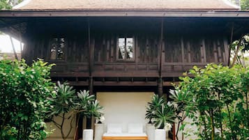 A traditional wooden structure with a bench in front, surrounded by potted plants.