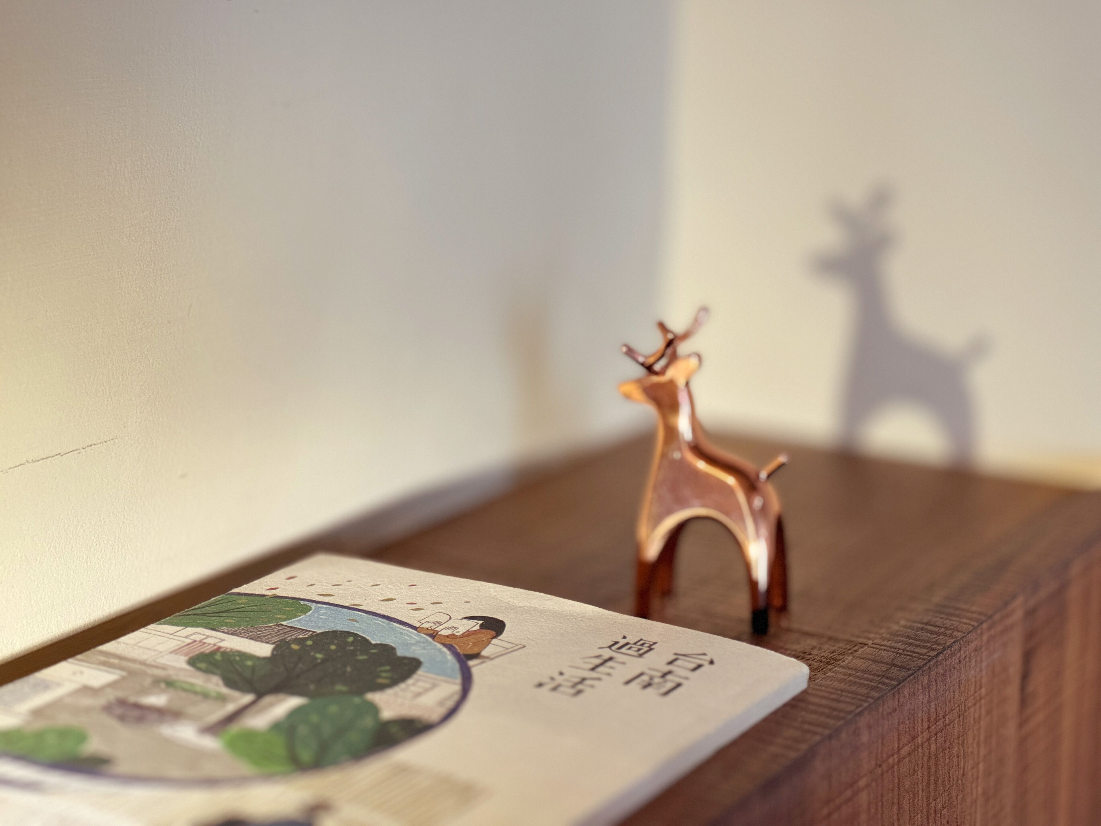 Een houten plank met een klein koperen hertenbeeldje en een kaartje met tekst en illustraties.