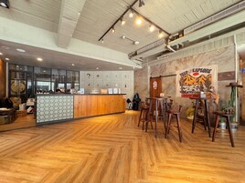 Um restaurante com chão de madeira, balcão com divisória estampada e decoração de parede com tema de deserto.