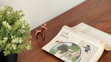 A wooden table with a potted plant, a small deer figurine, and an open book with illustrations.