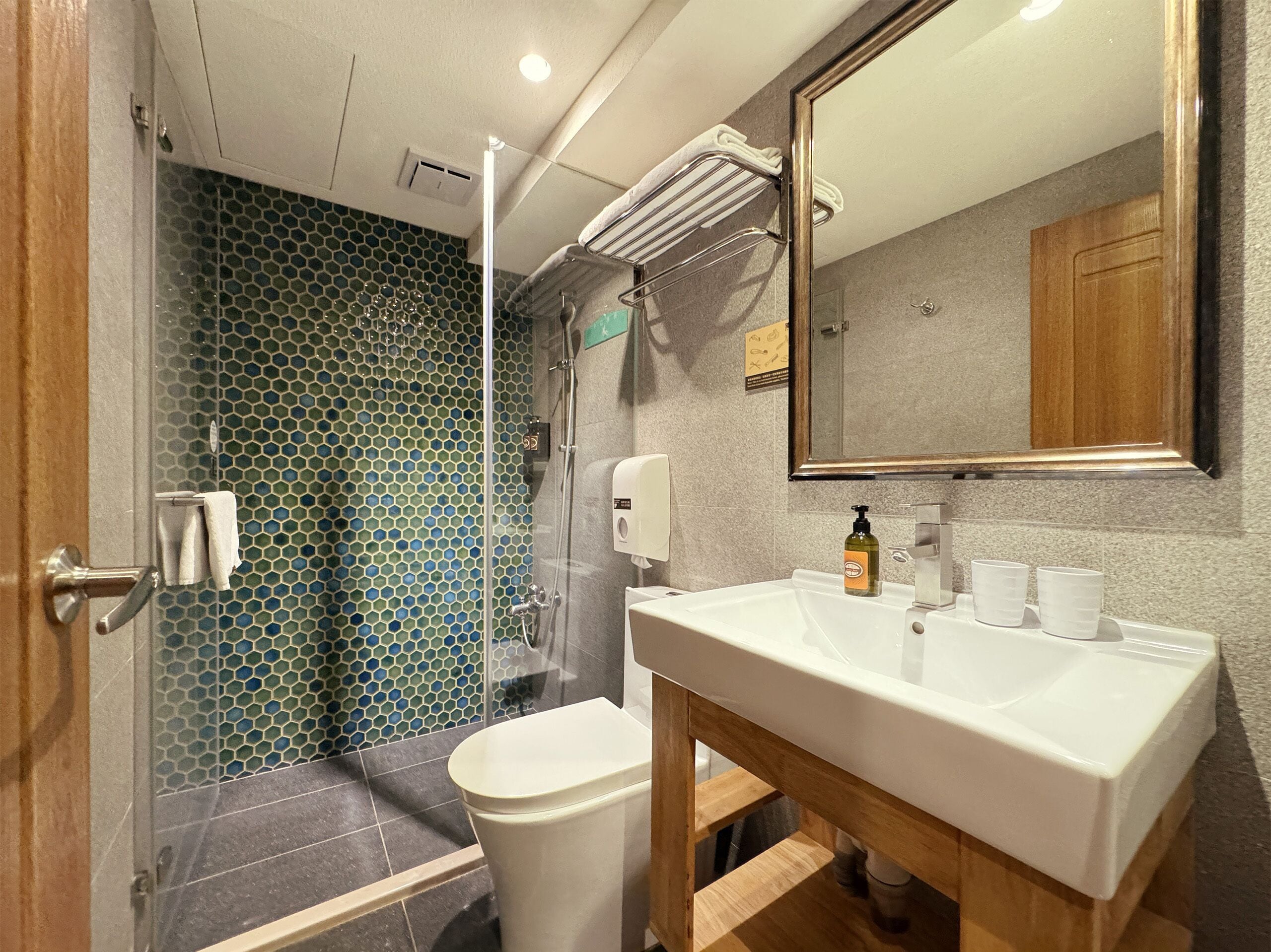 A bathroom with a shower, toilet, sink, and a mirror.
