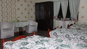A room with two single beds, a small table with chairs, a wardrobe, and a window with curtains. - Sara's Guest House (Ulaanbaatar)