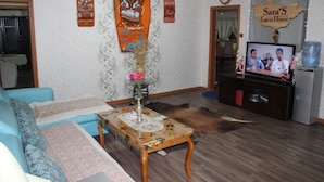 A living room with a sofa, a coffee table with a vase, a television, and a sign reading "Sara's Guest House". - Sara's Guest House (Ulaanbaatar)