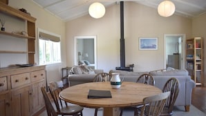 A cozy living room with a round wooden table, comfortable seating, a fireplace, and a bookshelf.