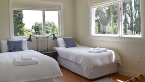 A room with two beds, a desk, and large windows.