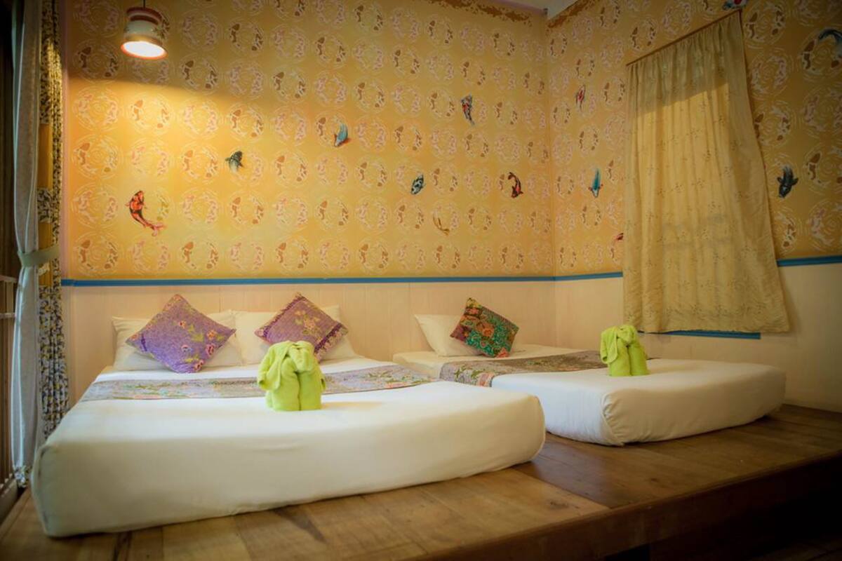 Une chambre avec deux lits, un banc en bois et un papier peint à motifs.
