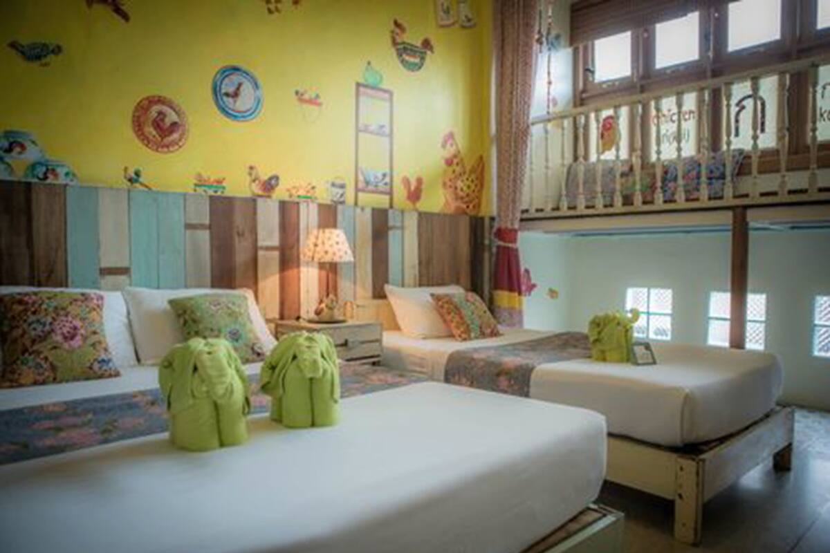 Une chambre adaptée aux enfants, avec deux lits, des décorations murales colorées et une fenêtre donnant sur un paysage agréable.