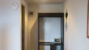 A hallway with a coat rack, a clock, and a thermostat on a shelf. - Cottage Hill at Lanta (Ko Lanta)
