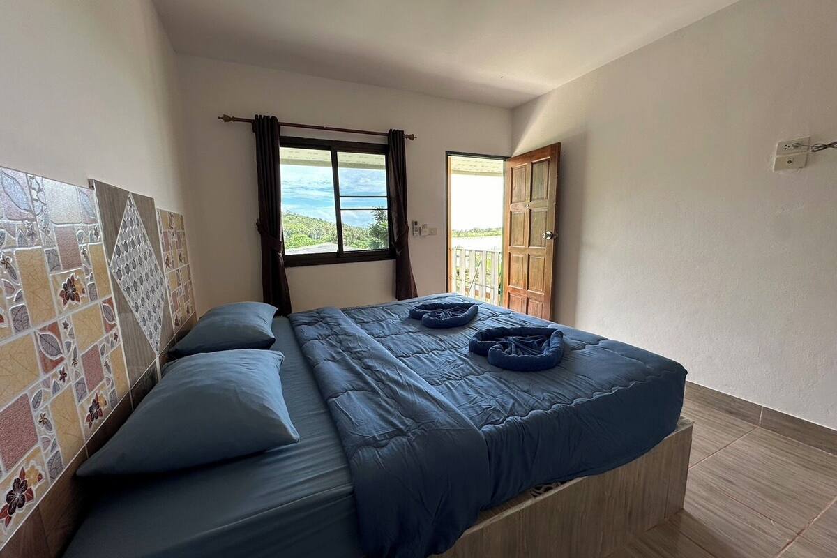 Quarto com uma cama, vista para o exterior e parede revestida de azulejos.