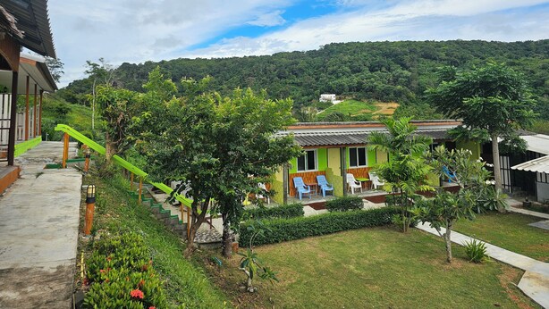 A green-roofed building with outdoor seating and a staircase leading to a wooden deck. - Cottage Hill at Lanta (Ko Lanta)