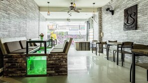 Een modern interieur met een bakstenen muur, een aquarium met groen verlichting, en een zithoek met tafels en stoelen.