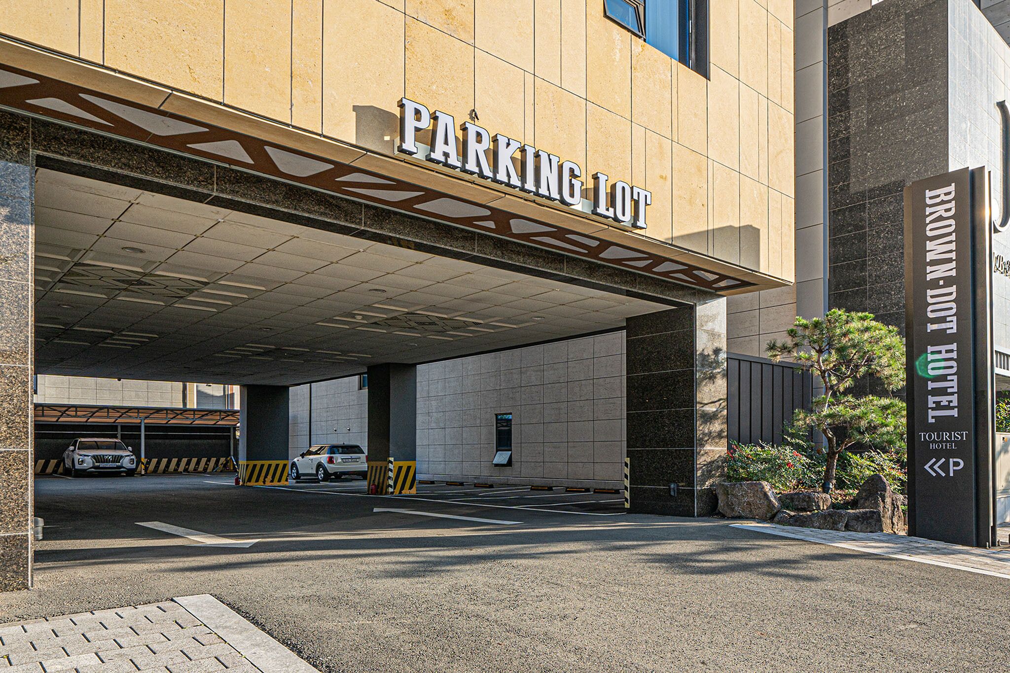 A parking lot entrance with a sign reading "PARKING LOT" and a "BROWN-DOOT HOTEL" sign nearby.