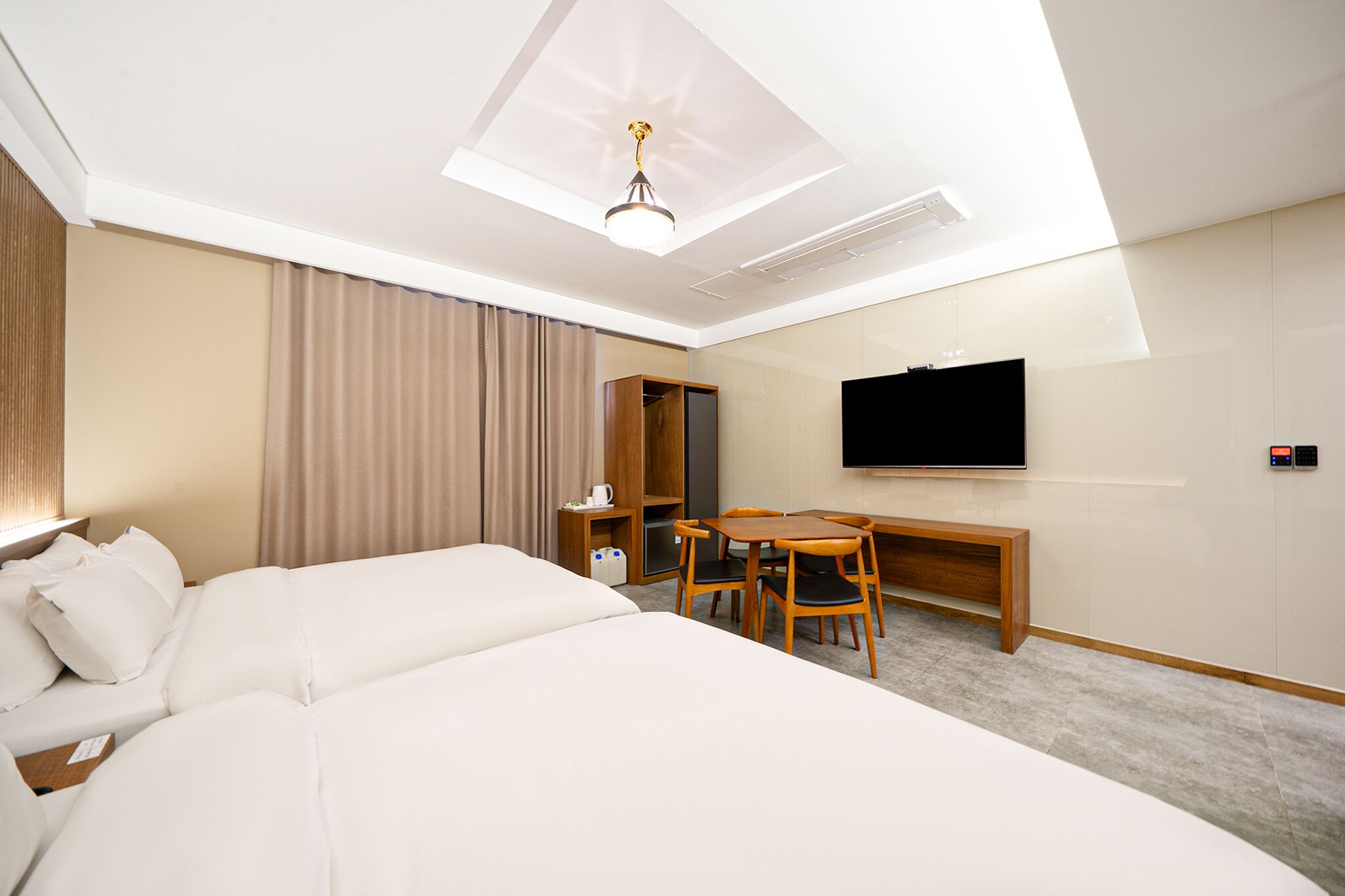 A hotel room with a large bed, a desk with two chairs, a television, and a wardrobe.