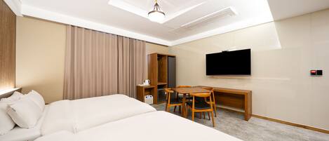 A hotel room with a large bed, a desk with two chairs, a television, and a wardrobe.
