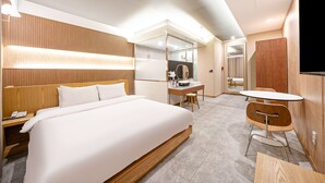 Una camera d'albergo moderna con un letto grande, una scrivania con una sedia, un tavolino e una televisione.