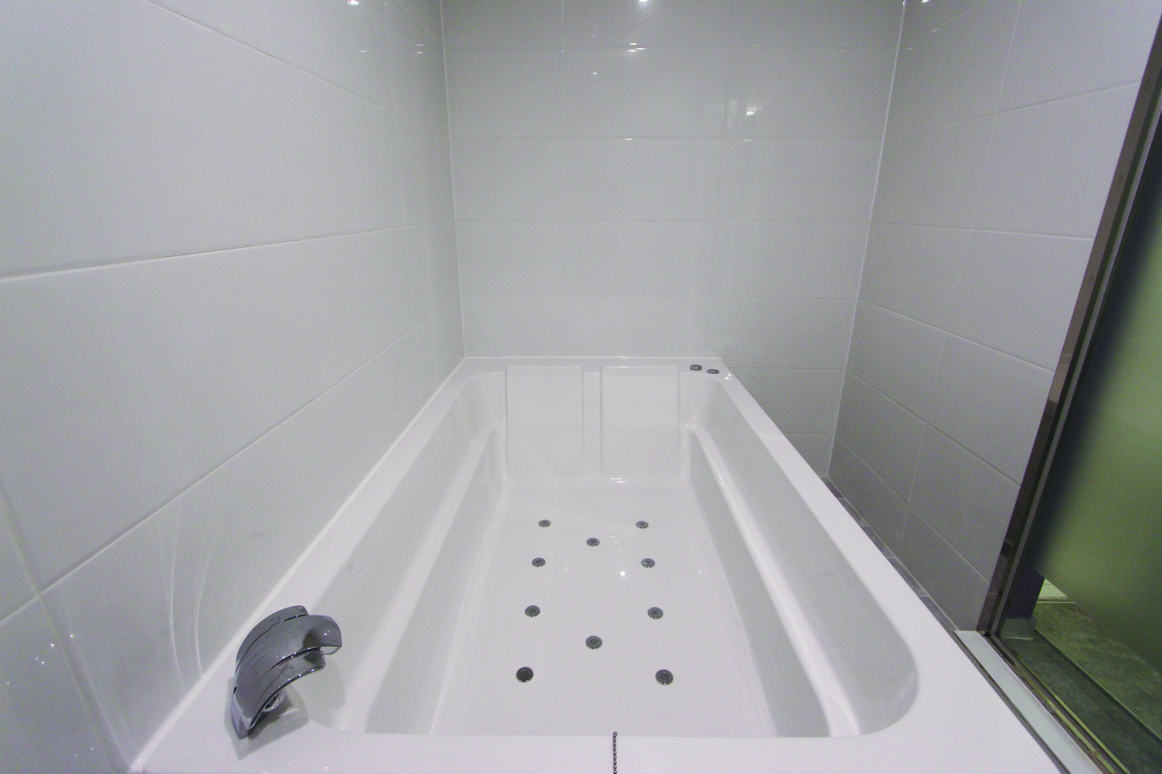 Un baño moderno con una bañera blanca, zona de ducha y puerta de cristal.