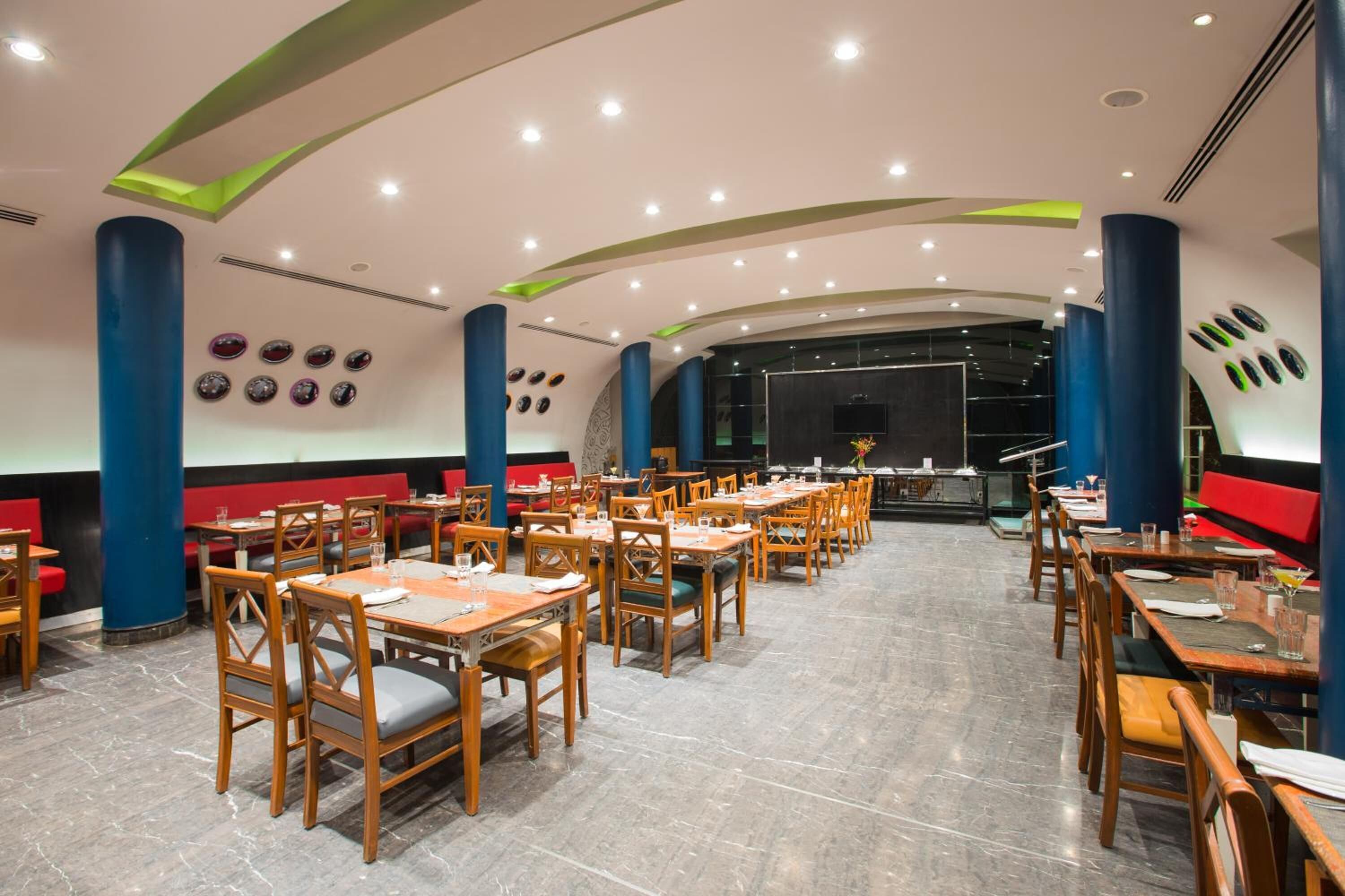 Ein geräumiges Restaurant mit Holztischen und -stühlen, einem Marmorboden und einem modernen Deckenstil.