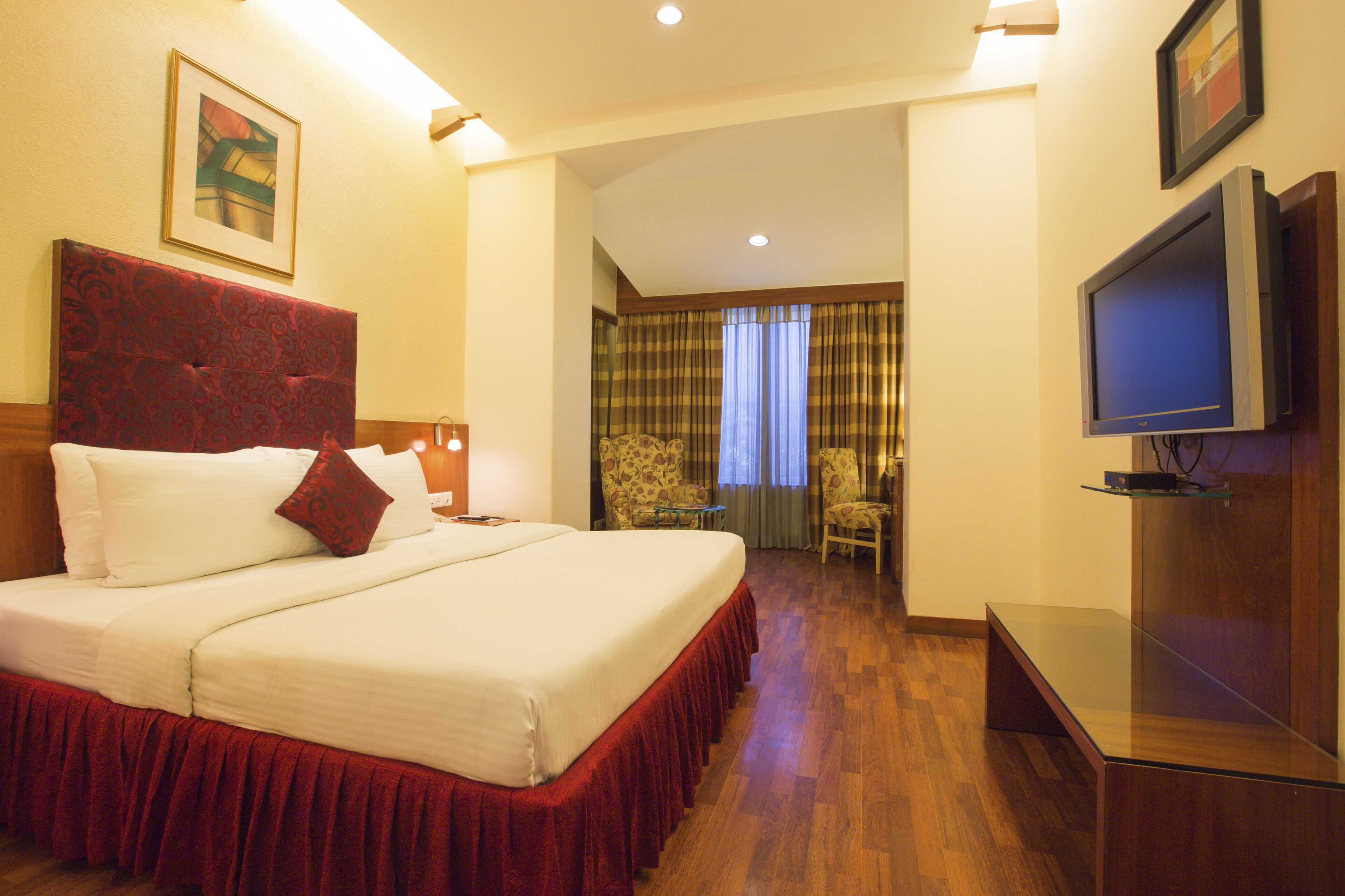 A hotel room with a large bed, a television, and a desk.