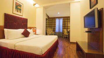 A hotel room with a large bed, a television, and a desk.