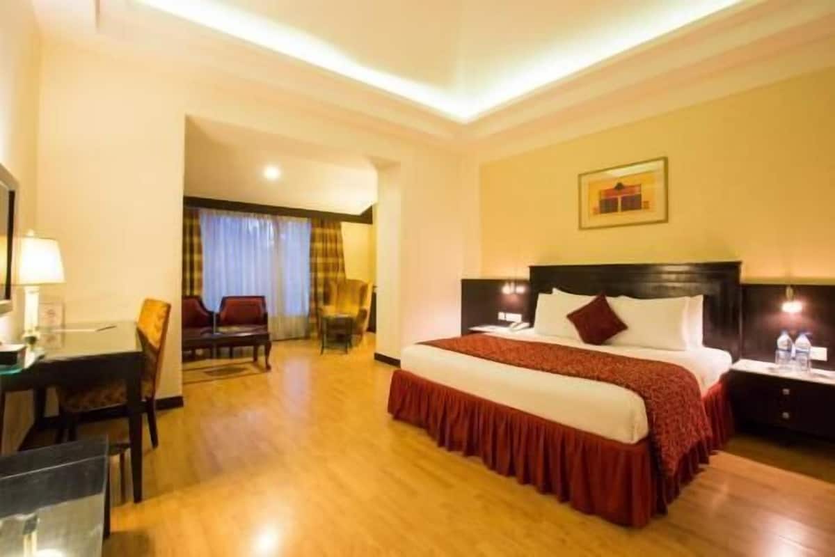 A hotel room with a bed, bedside tables, a desk, and a chair.