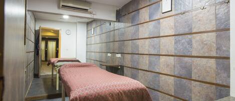 Ein Zimmer mit zwei Betten, einer hölzernen Bank und einer Wand mit gefliestem Mauerwerk und einem gerahmten Zertifikat.