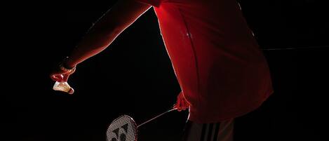 A person playing badminton on a wooden court.