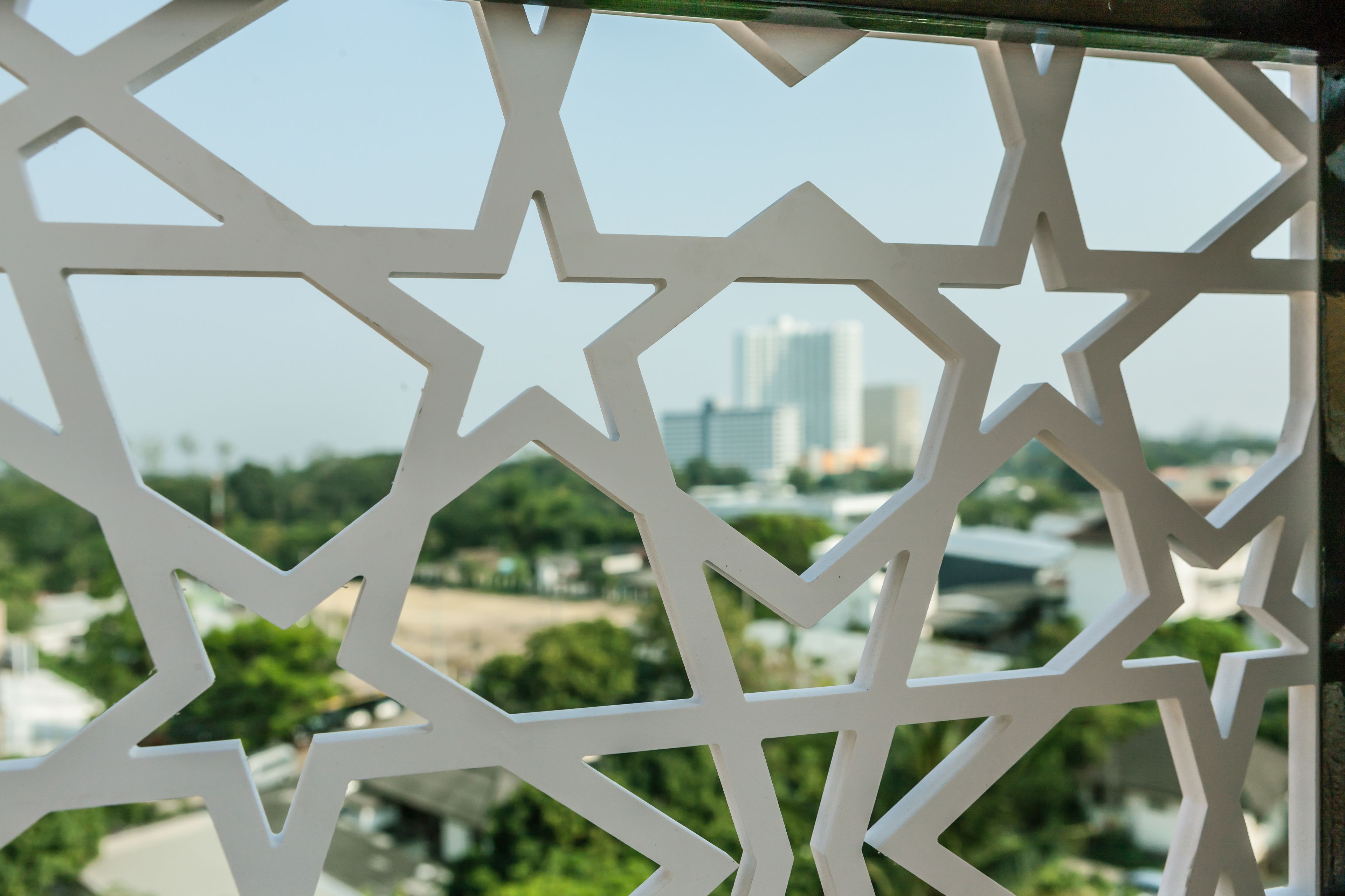 A view through a geometric window with a cityscape in the background.