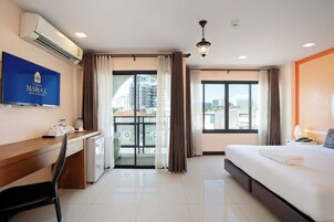 Una habitación de hotel con cama, escritorio, televisión y balcón con cortinas.