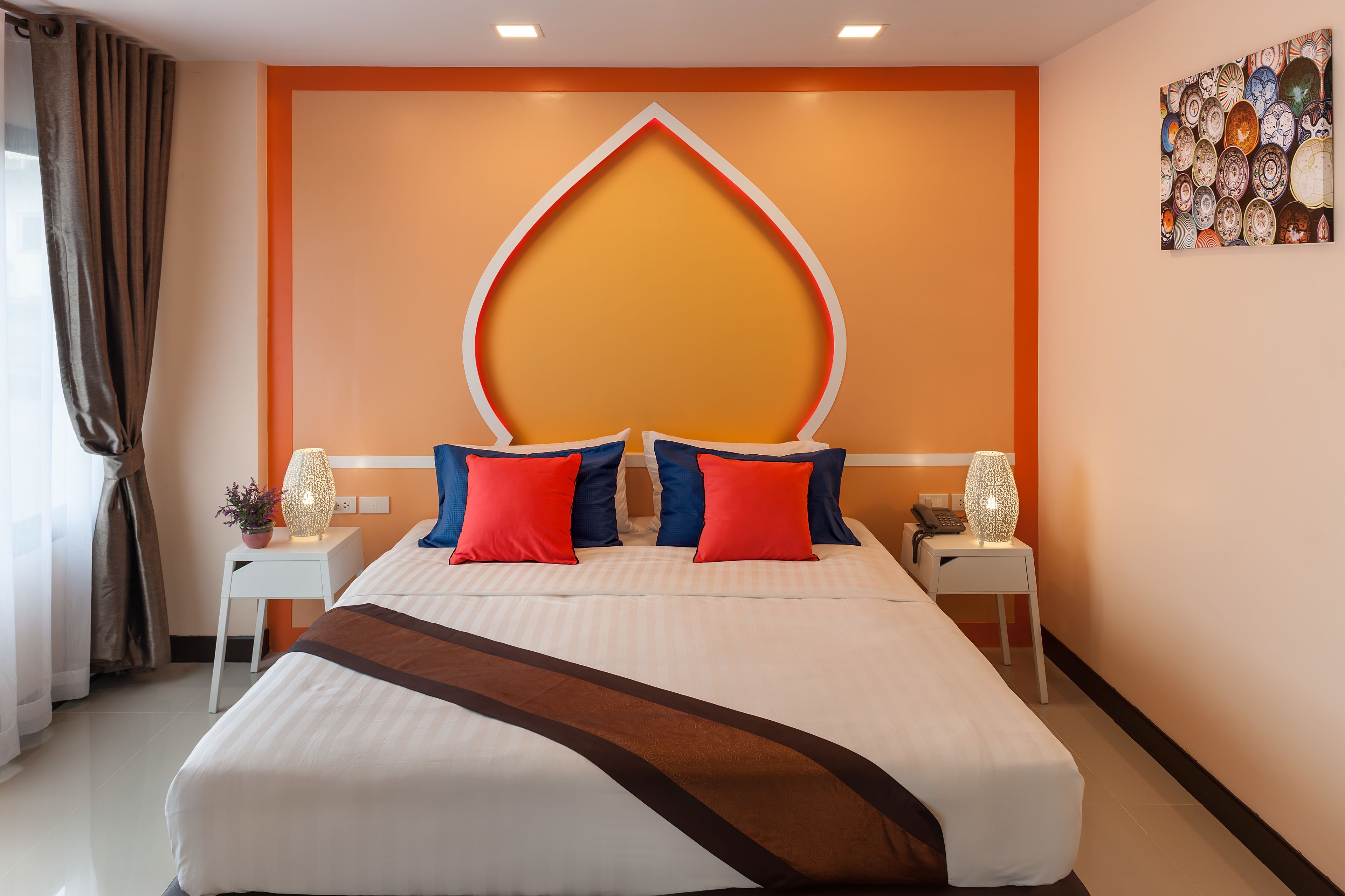 Una camera d'albergo con un letto grande, due comodini, un pannello decorativo a parete e un'opera d'arte appesa al muro.