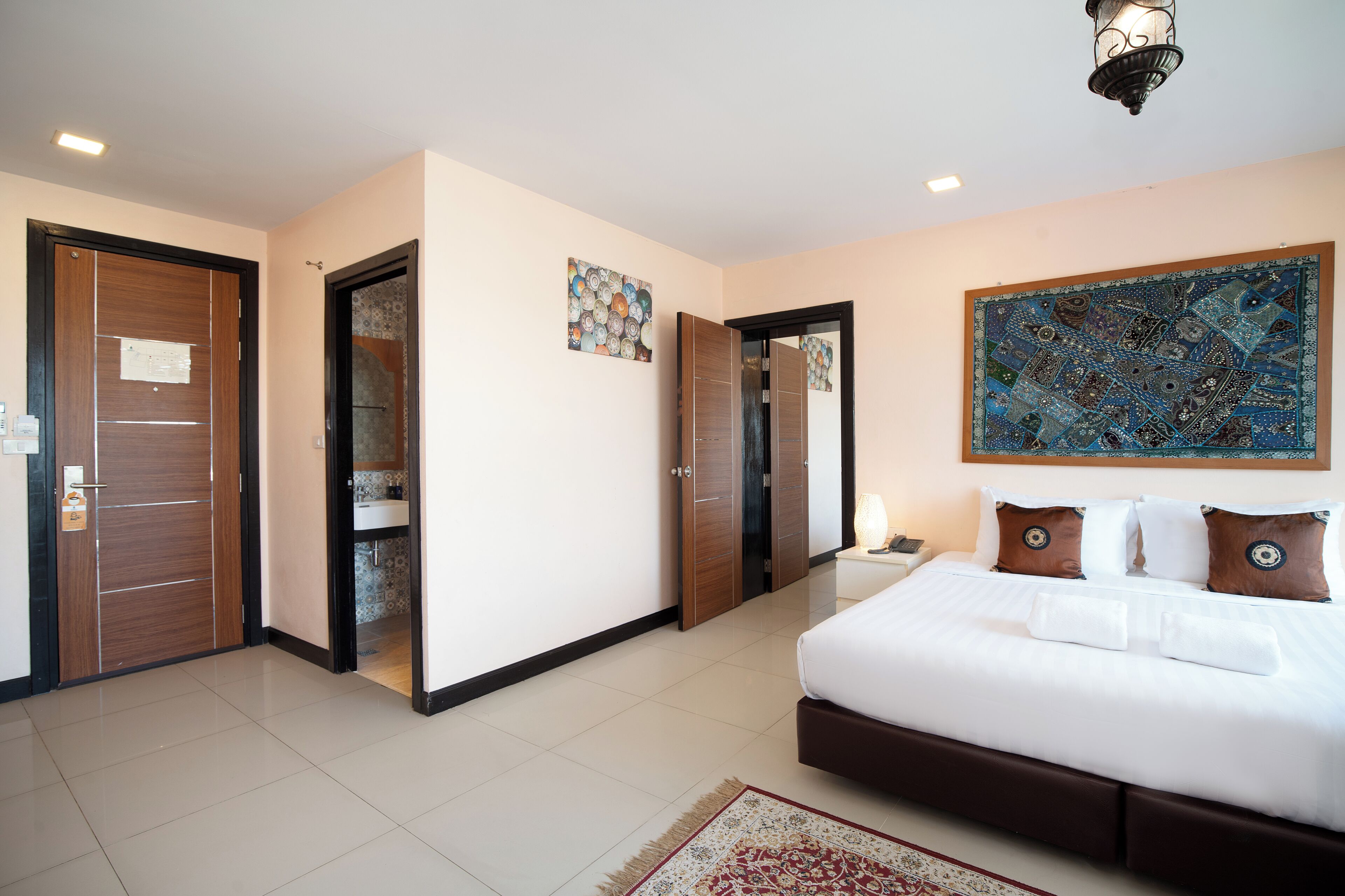 A hotel room with a large bed, a nightstand, a mirror, and a wall-mounted artwork.