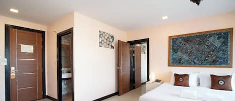 A hotel room with a large bed, a nightstand, a mirror, and a wall-mounted artwork.