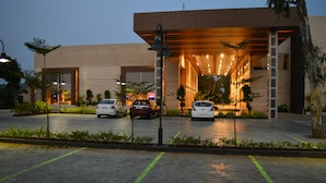 Un bâtiment moderne doté d’une entrée abritée, d’un espace de stationnement avec des places délimitées et d’un jardin bien entretenu.